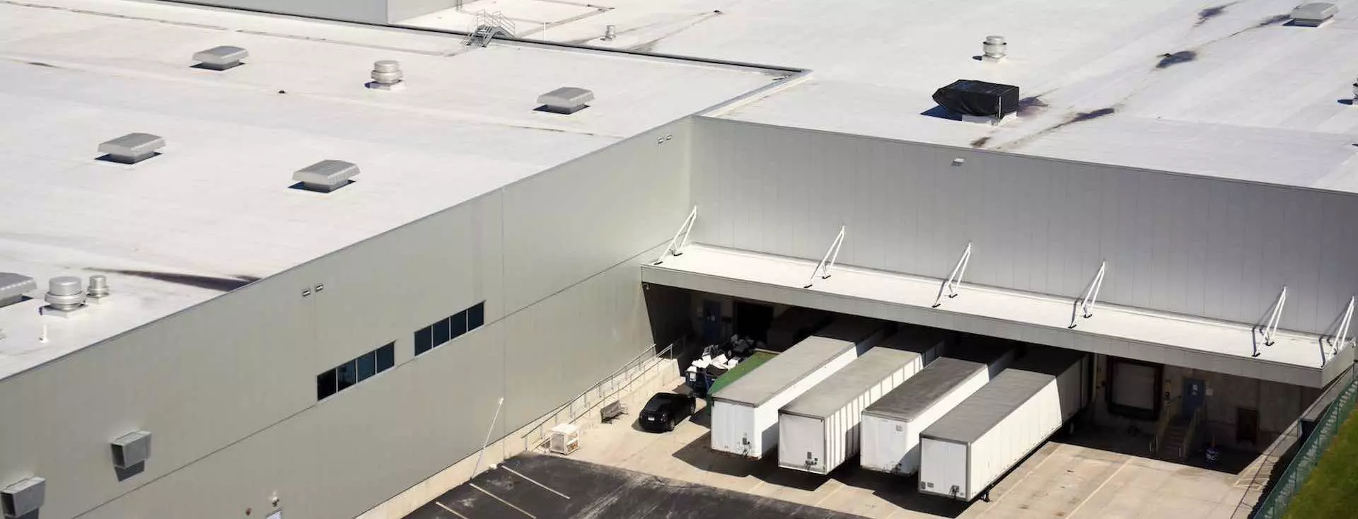 Industrial warehouse building with flat, commercial roof, covered with white TPO roofing